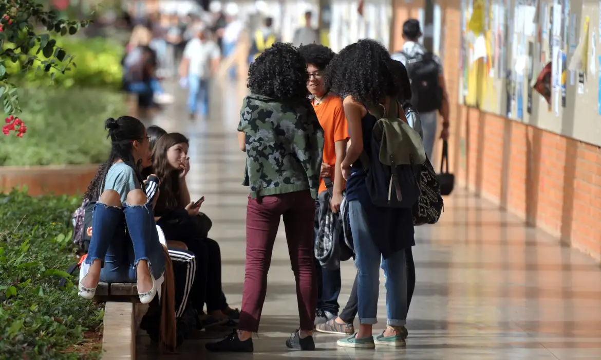 Imagem de alunos do Pé de Meia conversando no corredor do colégio.