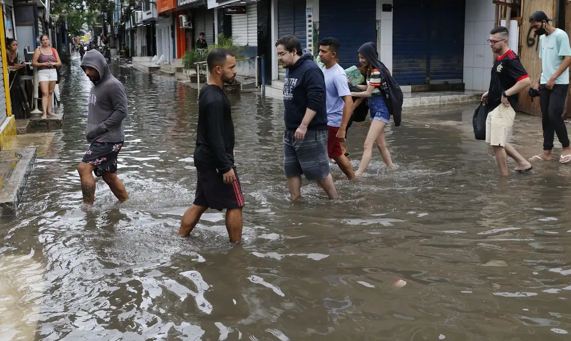 Imagem de pessoas andando no meio de um alagamento 